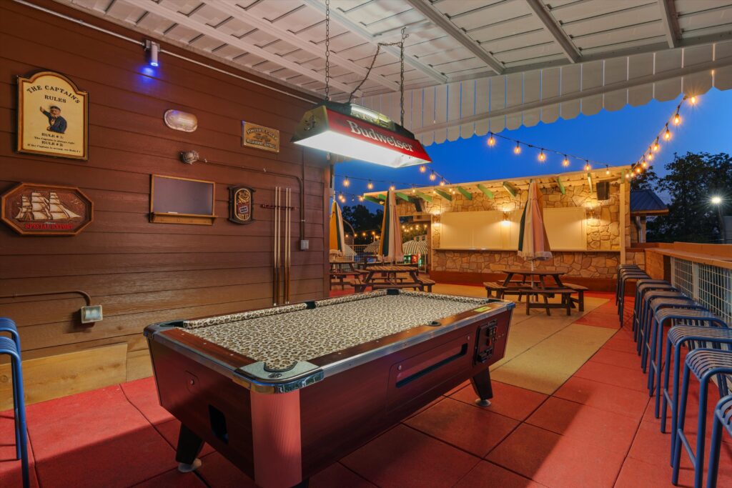The second-floor features a shaded seating area and a cheetah-print pool table.
