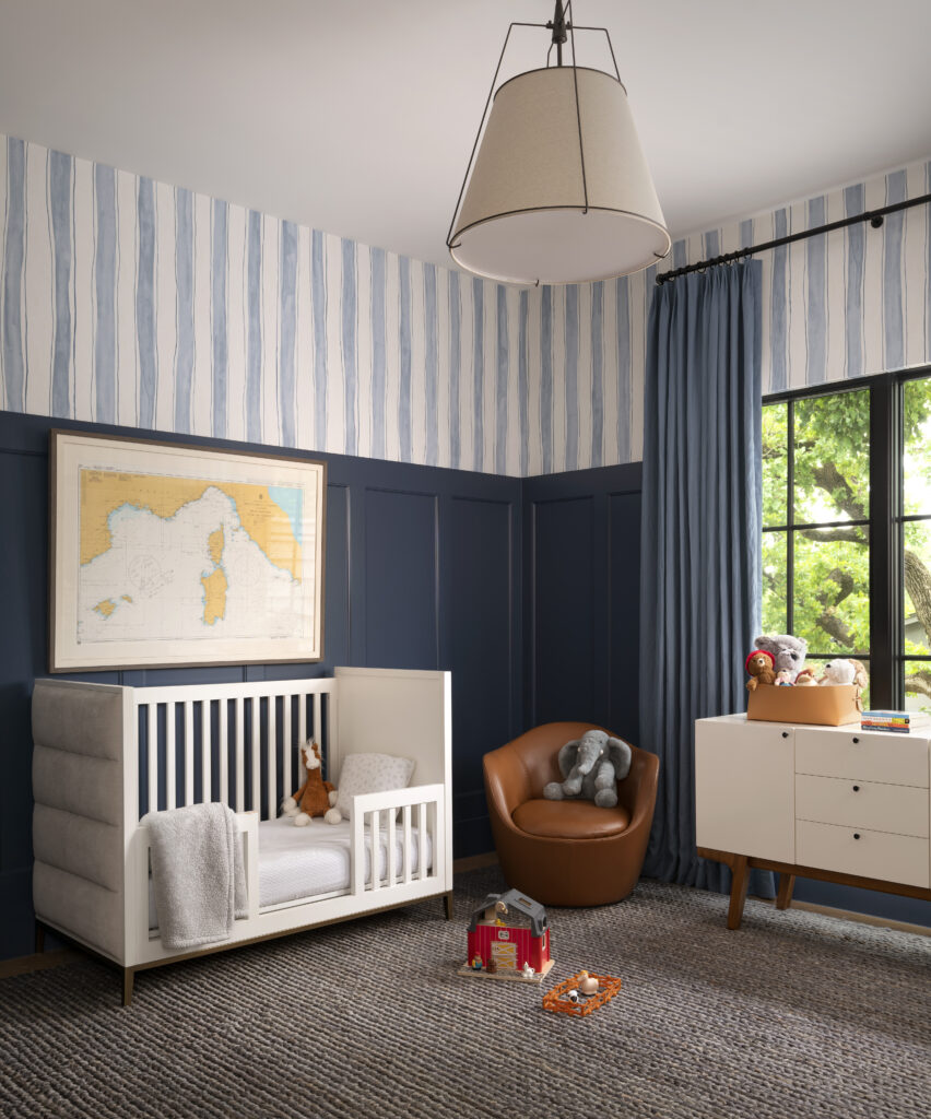Boy's room with a white crib, blue wallpaper and stuffed animals.