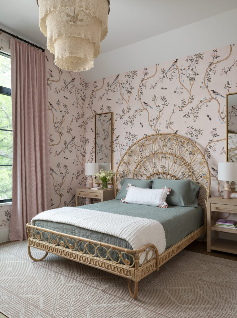 Girl's room with a green comforter, a decorative wicker headboard, and pastel pink wallpaper.