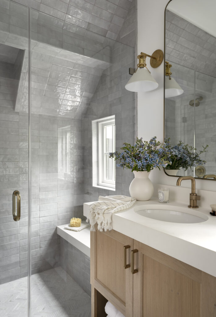 Guest house bathroom with a gray tiled shower and a glass door.