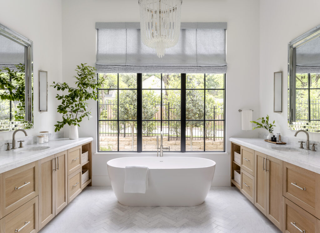 Main bathroom with a white claw tub, marble sink countertops and tan wood cabinets.