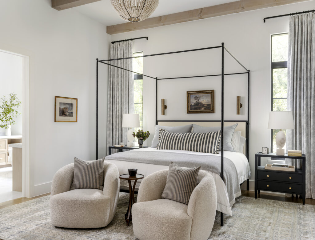 Main bedroom with canopy bed and a white comforter with grey pillows and blankets.