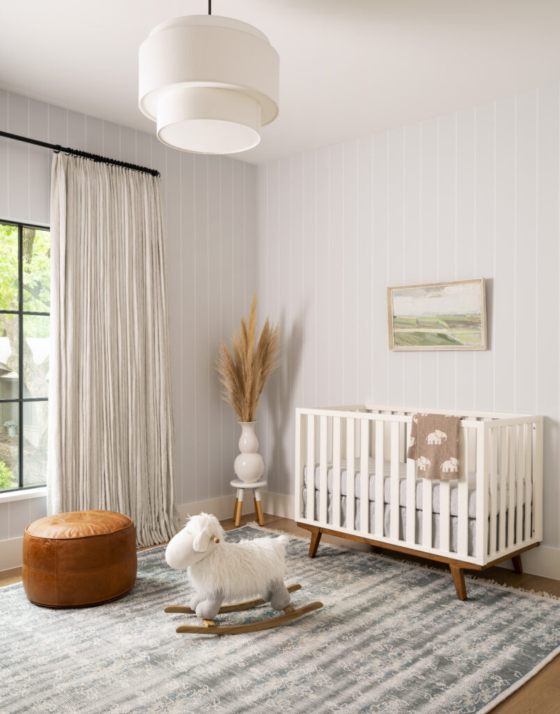 Nursery room with a bassinet, sheep rocking chair, and white shiplap walls.