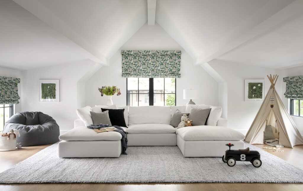 Playroom with vaulted ceilings, a white couch, gray bean bag, and a tan tepee.