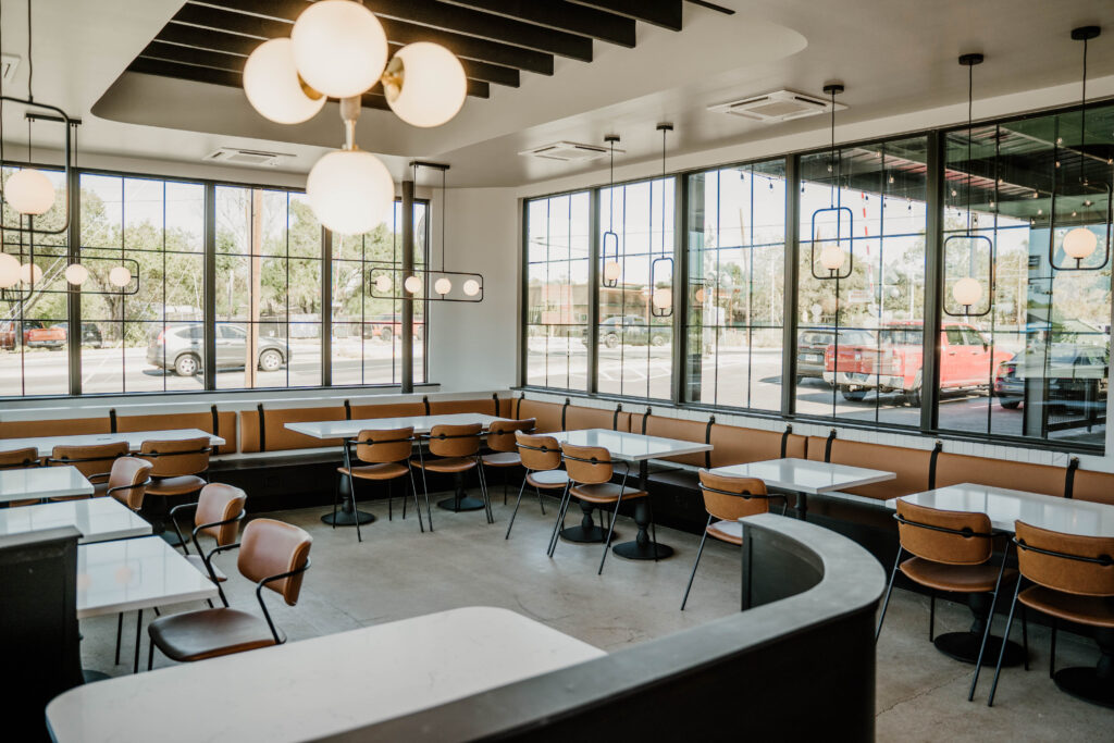 The dining room at Black Gold, featuring cement floors, leather-accented furniture, and sconce chandeliers. (Photo by Randi Reding)