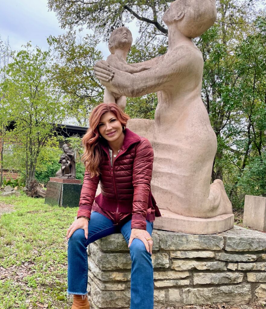 Carla Umlauf, granddaughter of sculptor Charles Umlauf, stands beside his “Mother and Child” sculpture at the UMLAUF Sculpture Garden & Museum in Austin