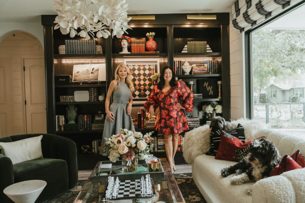 Brandy Fons and interior designer Jenny Mason in the entertainment room, which features a bookshelf wall adorned with art pieces and vases with florals to complement the space. (Photo by Lemon Woman Photography)