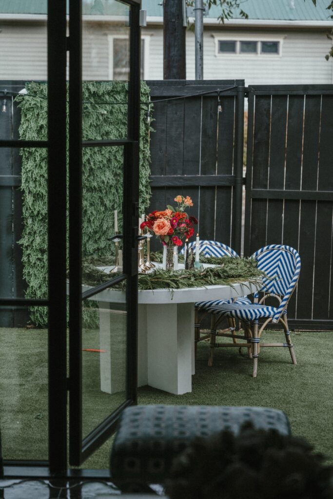 The backyard seating area features a circular white table surrounded by blue and white geometric-designed chairs. (Photo Lemon Woman Photography)