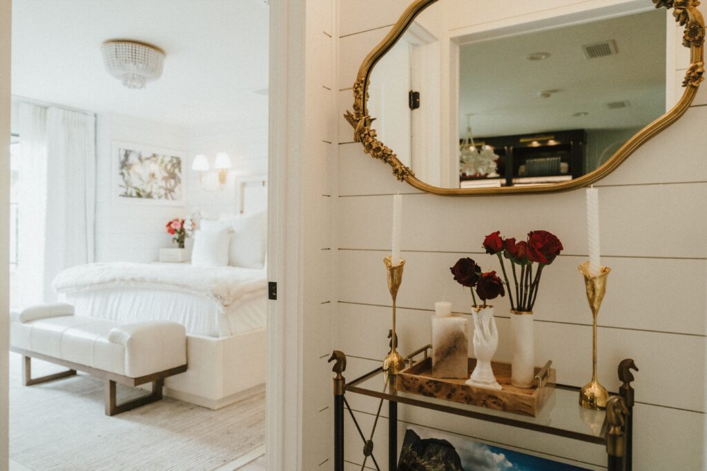 The primary bedroom features a chandelier, white shiplap, and brass and floral accents. (Photo Lemon Woman Photography)