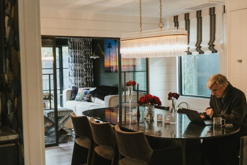 Brad Fons works on the dining room, which features a black marble table and a chandelier with brass accents. (Photo Lemon Woman Photography)