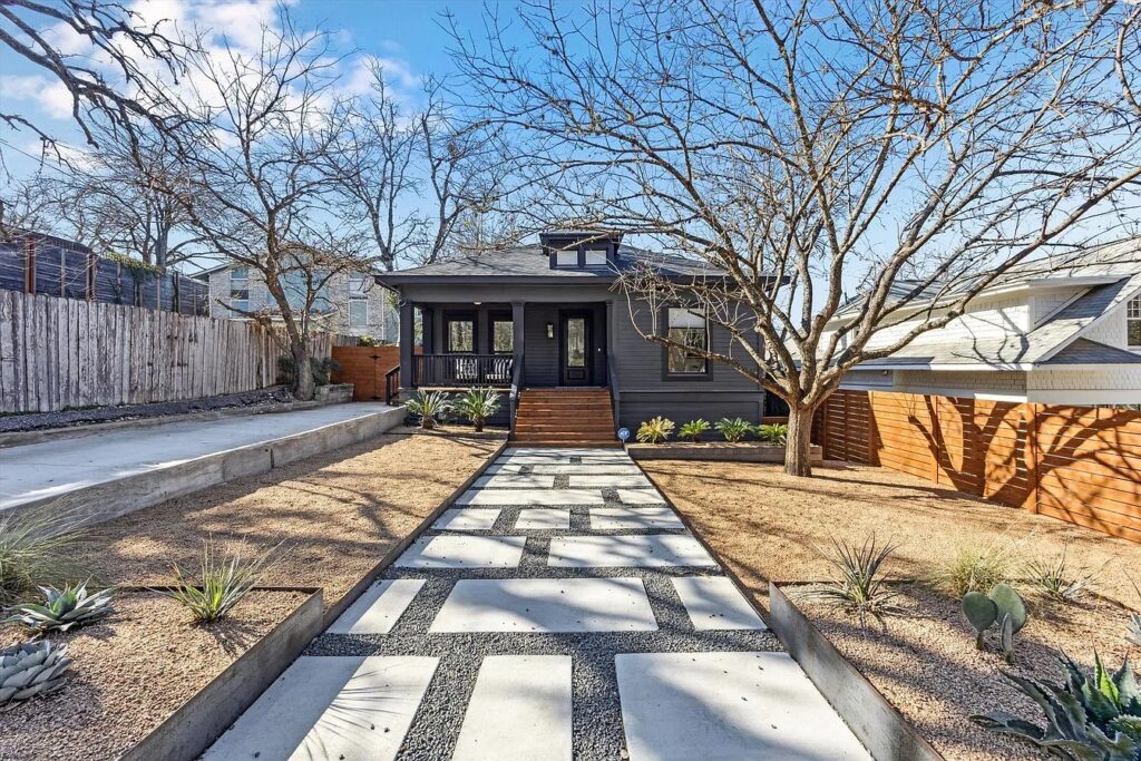 Austin home with a long driveaway and black brick exterior.