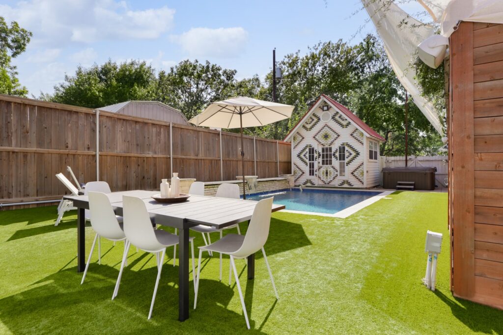 Large backyard with astroturf grass, a pool, and a detatched studio. (Photo courtesy of Moreland Properties)