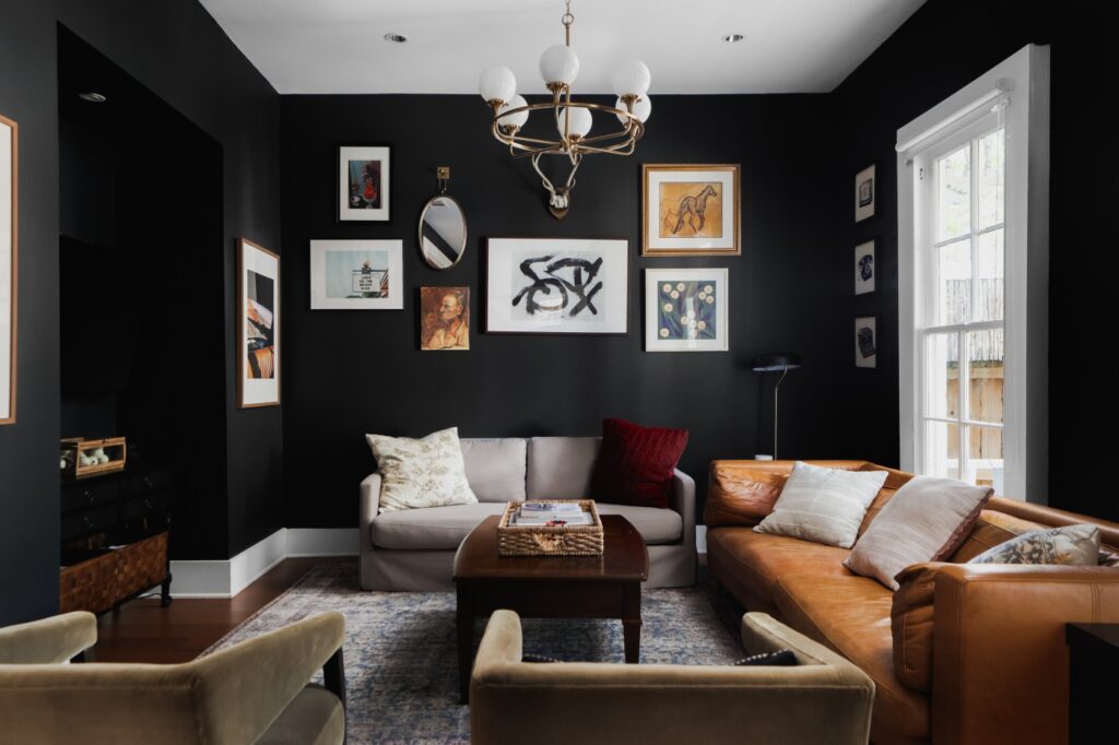 Living room with dark walls, chandelier, and light colored couch. (Photo courtesy of Moreland Properties)