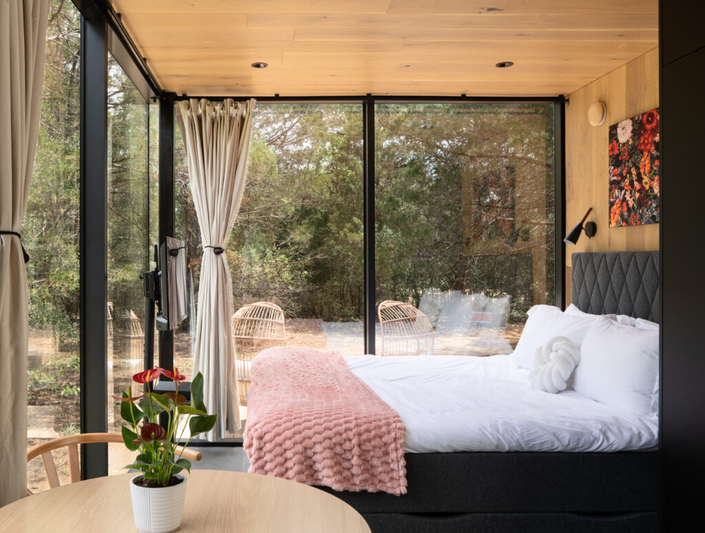The Bloom features a chic queen-size bedroom with floor-to-ceiling windows that reflect the surrounding pines.