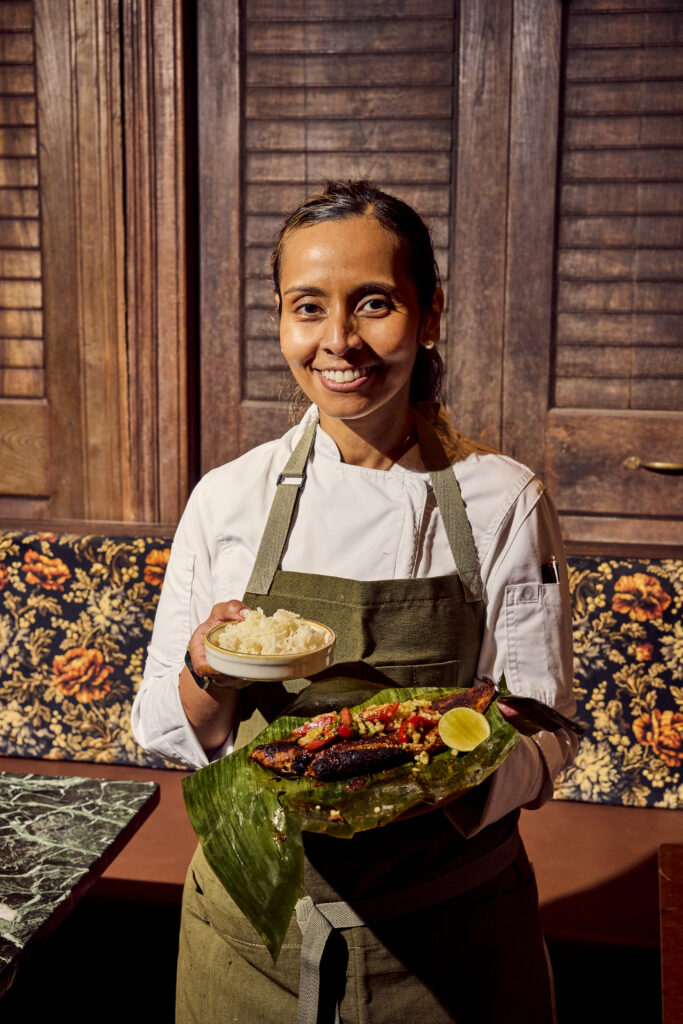 Chef Laila Bazahm holds a plate of sambal striped bass, her take on a Singaporean hawker dish, served with a side of Nasi Lemak—fragrant Hom Mali rice cooked in coconut milk—at Siti in Austin, Texas.