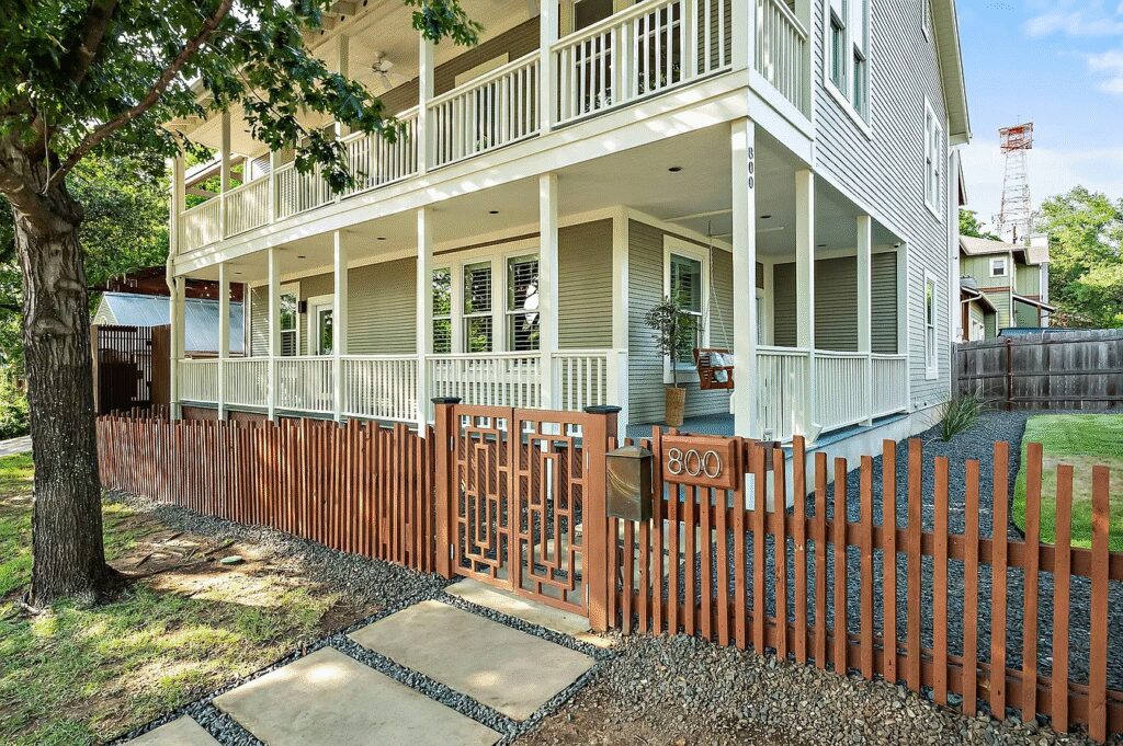 The exterior of 800 W. Lynn St., a two-story home that features a gated property with a wraparound porch.