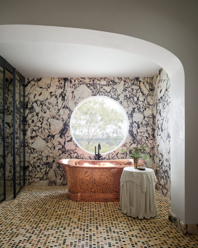 The primary bathroom stuns with terrazzo floors, custom marble slabs and a bespoke copper tub.