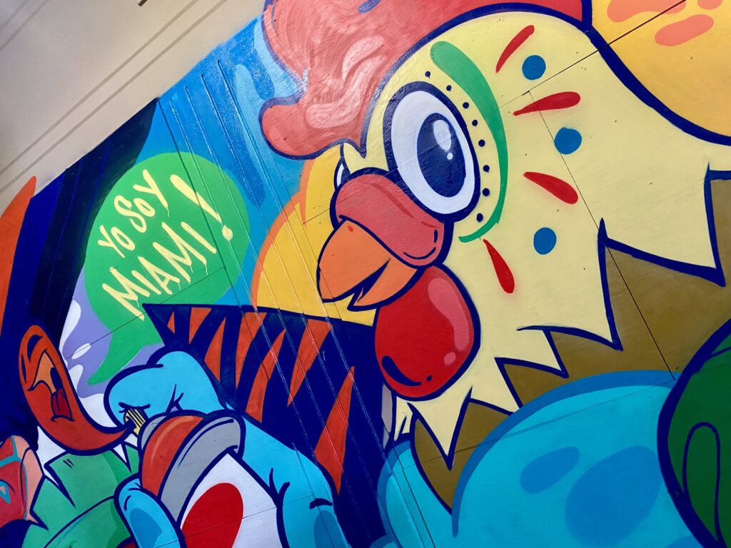 Mural depicting a chicken spray painting, with words that say "Yo Soy Miami."