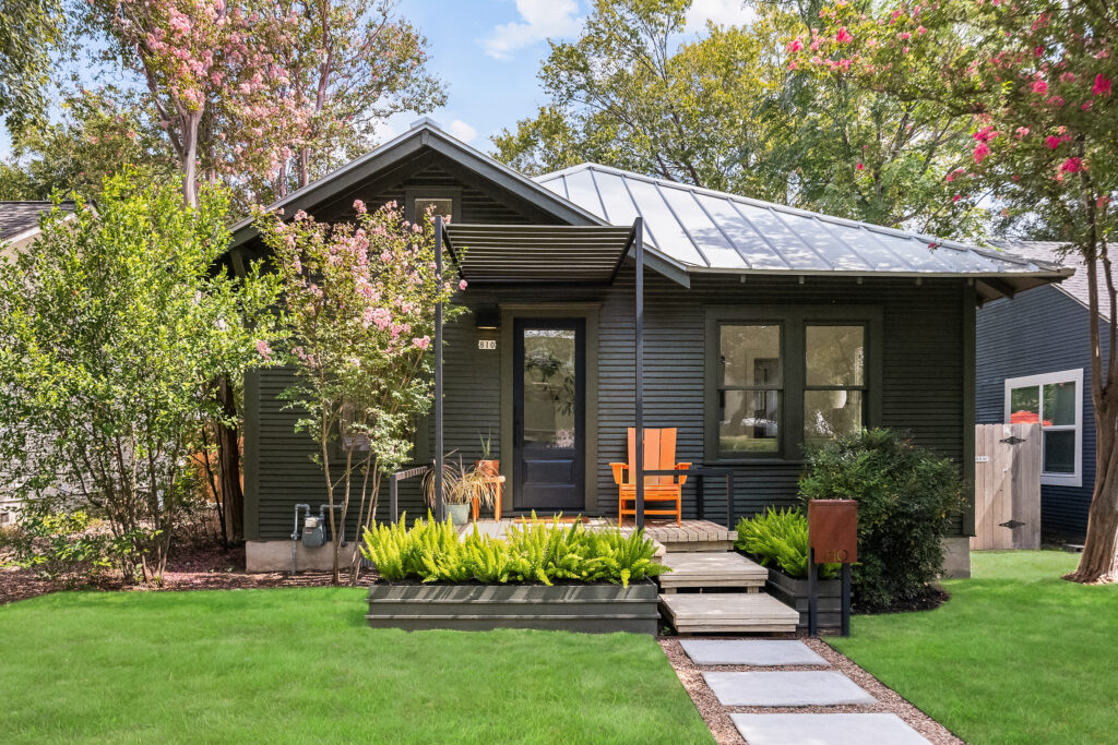 The front porch at 810 Keasbey St. in Austin features a bright orange lounge chair, with greenery framing the entrance. (Photo by Scott Hamilton)