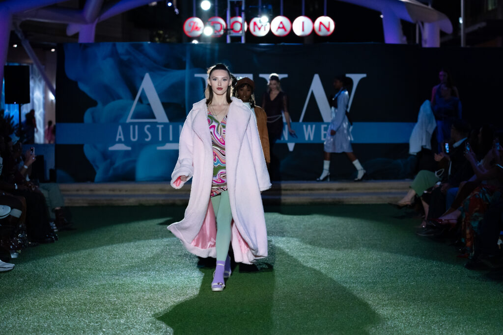 Woman in pink coat on the runway at Austin Fashion Week Fashion show