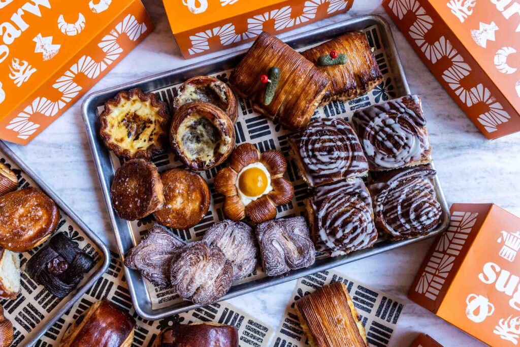 Bottom left morning bun Bottom right cinnamon roll Top right ham and cheese Center poppy Above poppy French onion danish To the left of that is egg tart under that is kouign amman_2