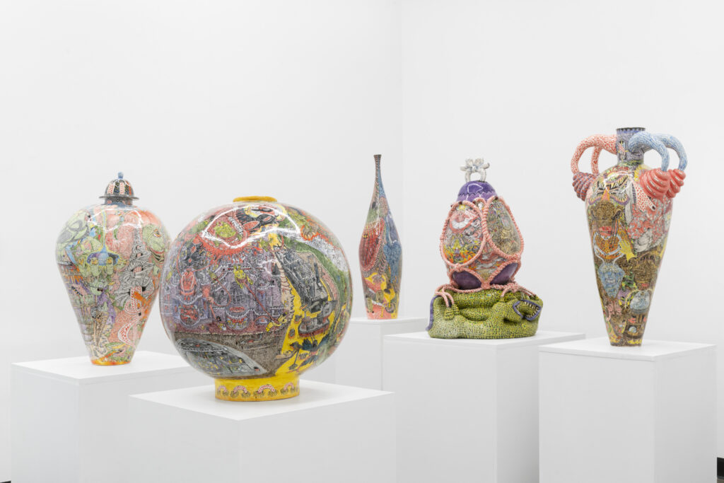Ornately designed glazed ceramic vessels by Charlie Hyman feature surreal hand-painted scenes of toads, mouths, rats and tangled forms.