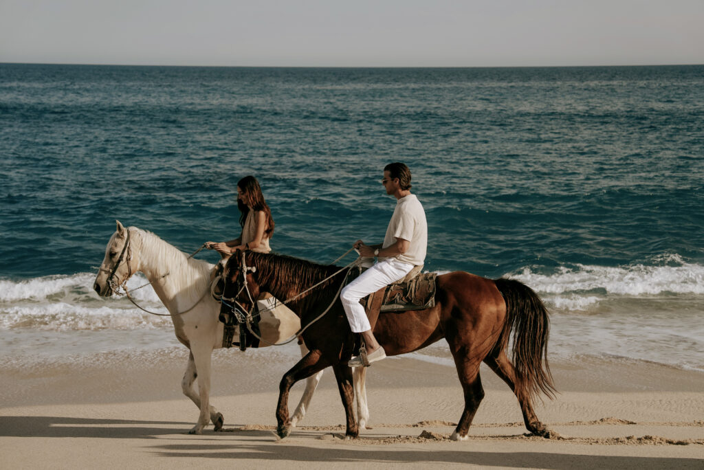 Couple riding horses on the beach.