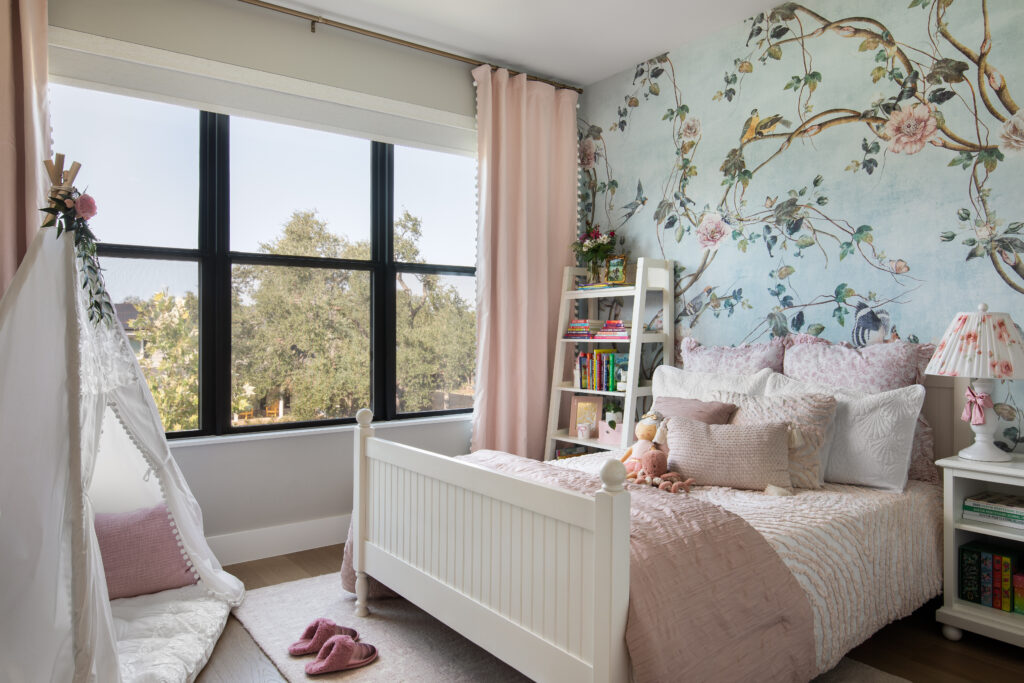 A child’s bedroom in the Bamford Drive home features soft pastels and whimsical wallpaper.