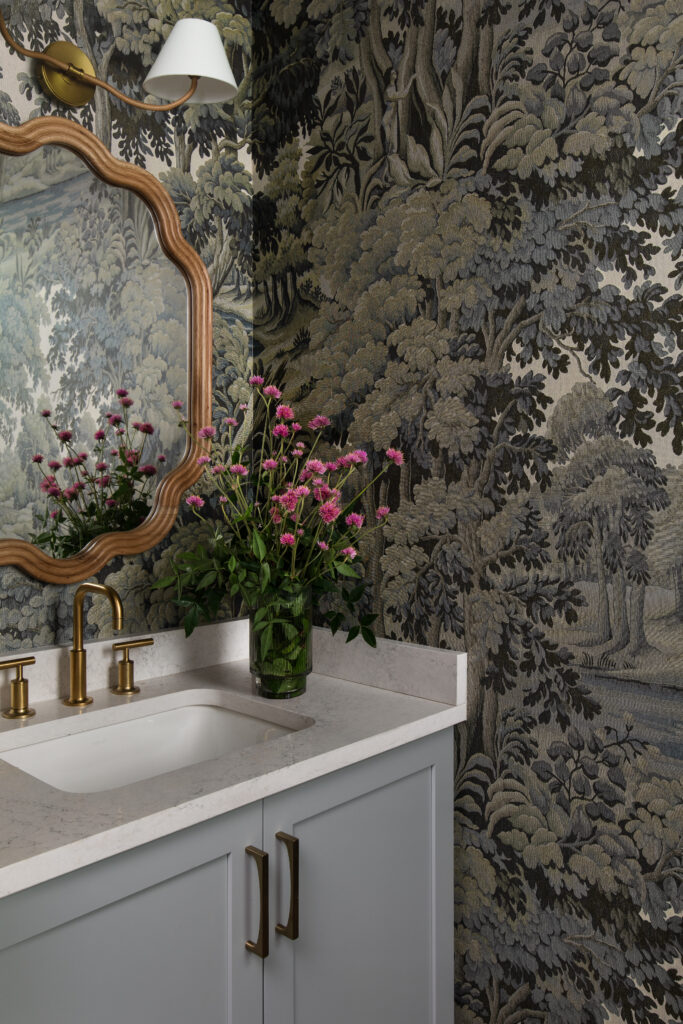 A bathroom in the Bamford Drive home features patterned wallpaper and gold-toned fixtures, adding character and visual interest to the space.