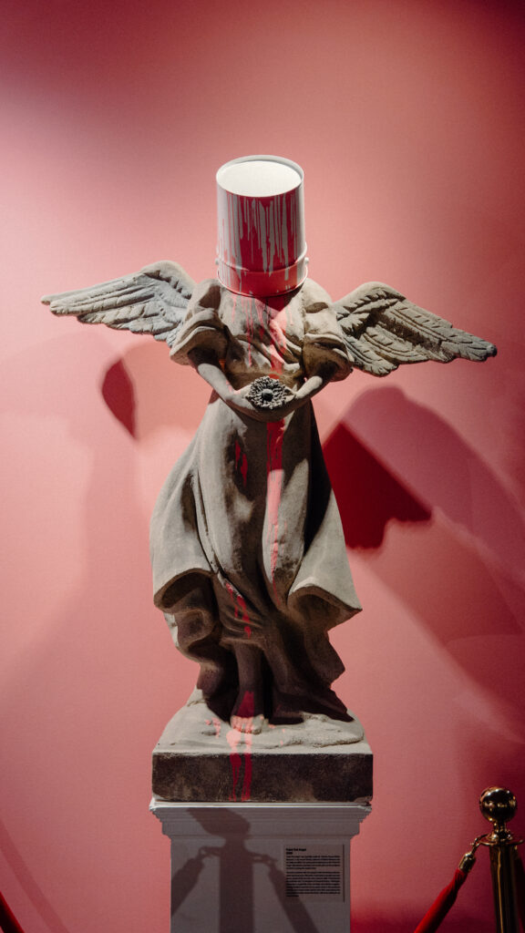 Upon entering guests are greeted with Banksy’s “Paint Pot Angel,” a replica of his 2009 sculpture.