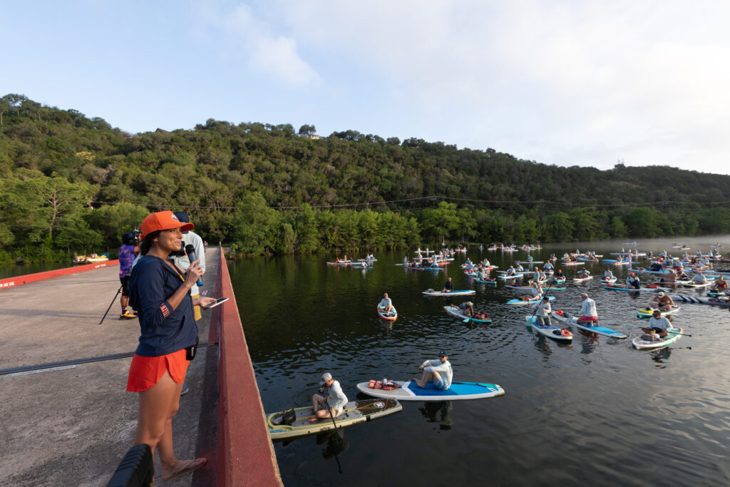 Flatwater Executive Director Alyssa Cornett addresses paddlers during the nonprofit’s 17th annual Dam That Cancer fundraiser on Monday, June 8, at Lake Austin.
