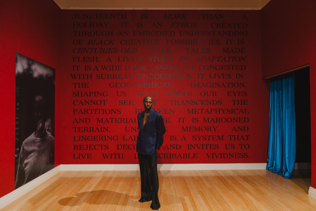 Artist Hakeem Adewumi stands inside his solo exhibition, “Seeing Further,” at the George Washington Carver Museum in Austin.