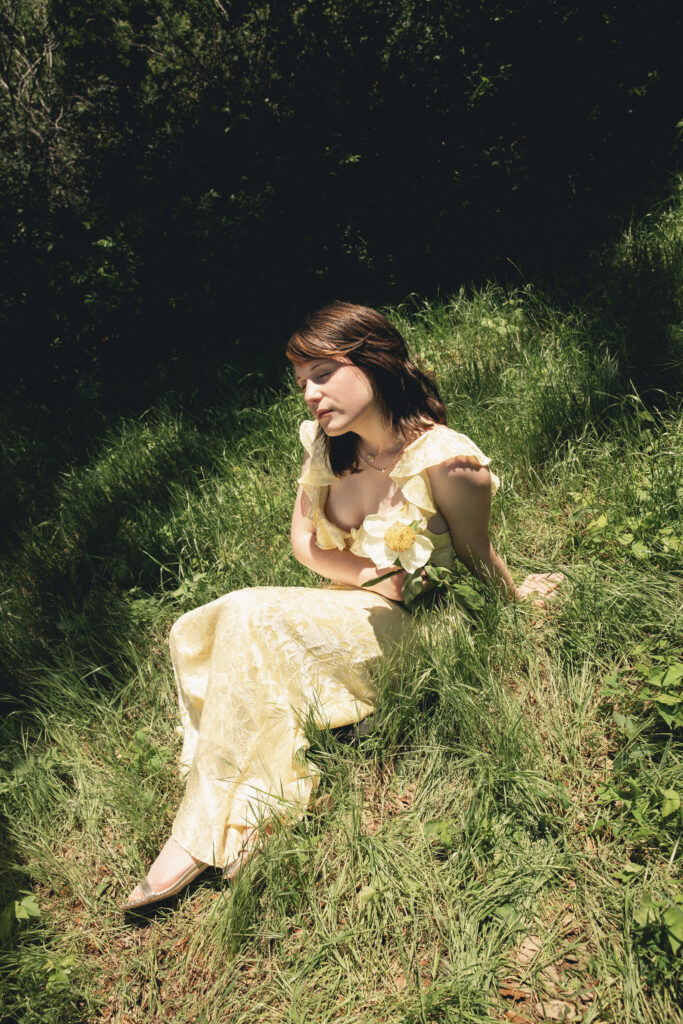 Designer Morgan McGaughey wears an Alice + Olivia Gemma Midi Dress in Butter with a Kendra Scott Mini Elisa and Abbie Strand Necklace, Adriana Scallop Frame Huggie Earrings and Elisa Scallop Frame Short Pendant Necklace.