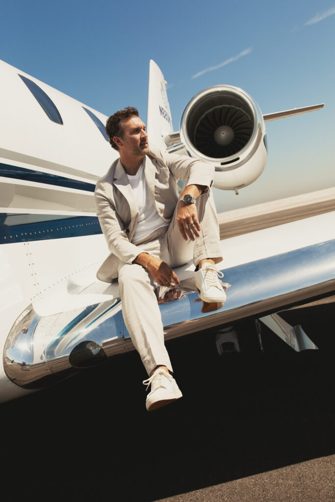 Matt Peters wears a khaki Theory suit available at Estilo Boutique