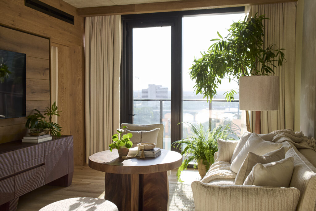 Living room area of 1 Hotel Austin featuring cozy couch, plants and balcony overlooking Lady Bird Lake