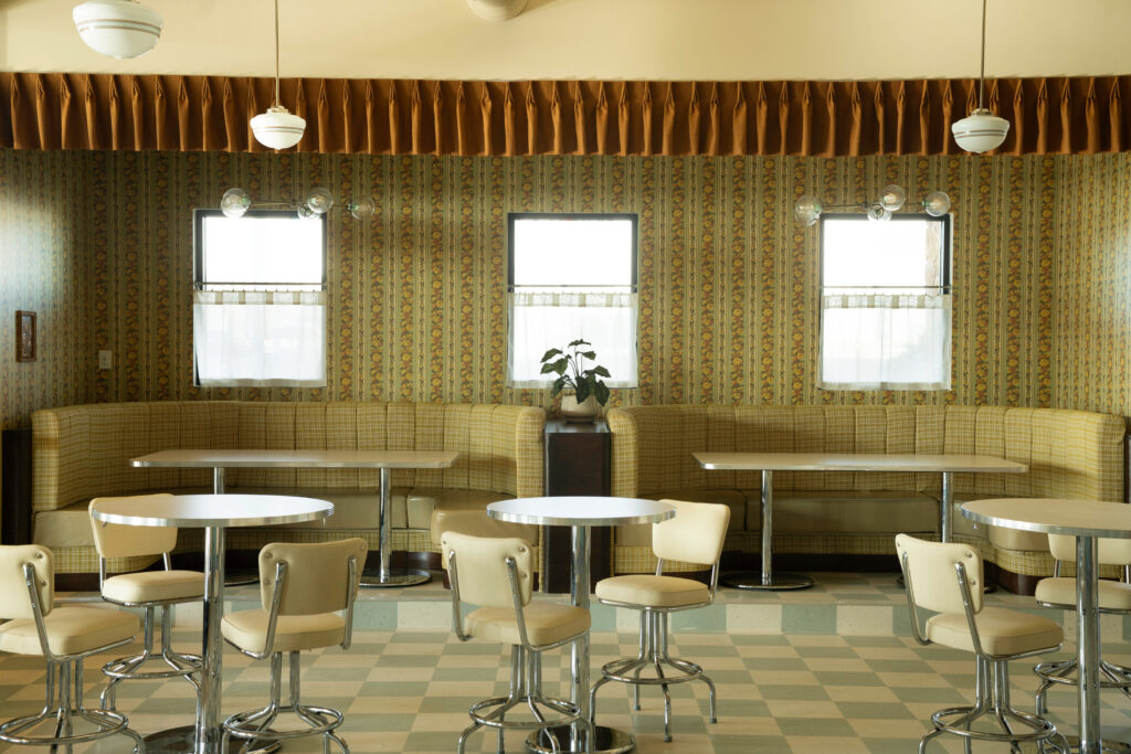 A Little Shady channels an old-school diner with chrome-edged tables, a checkered floor, cafe curtains and vintage 1970s wallpaper.