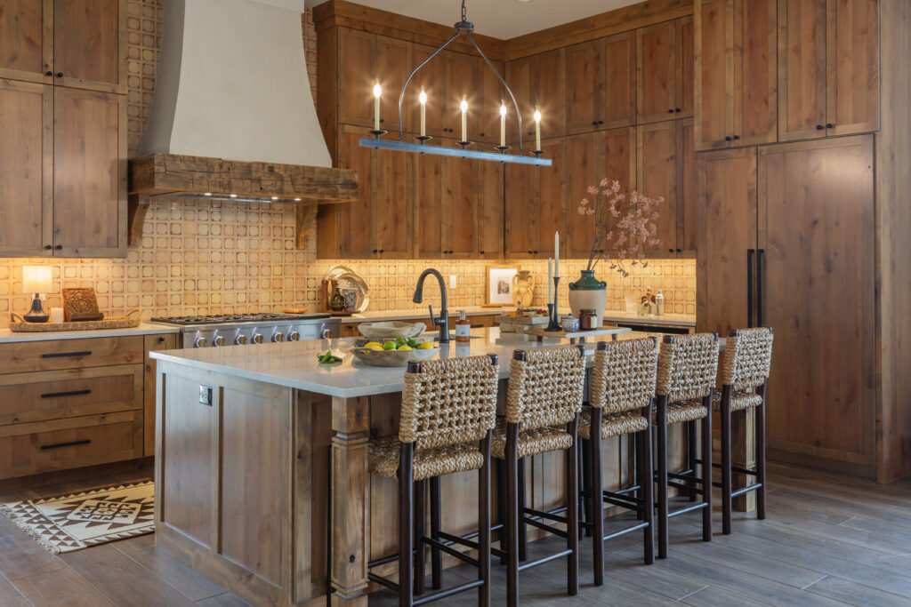 Hand-painted clay tile anchors the kitchen, where warm wood cabinetry and woven stools add to Casa Zia’s lived-in feel. (Photo by Brittany Dawn Photography)