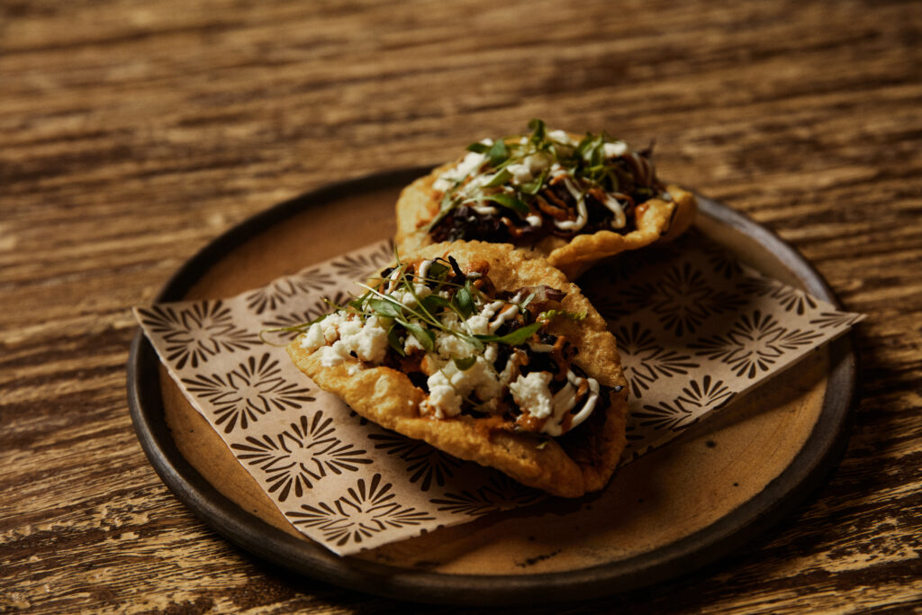 Escuela’s puffy tacos feature heirloom corn, smoked brisket, guacamole, salsa roja and queso fresco.