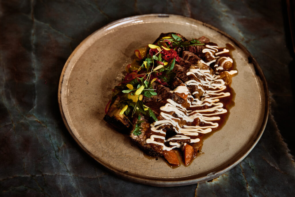 Escuela Fino’s short rib guisada is smoked for seven hours, finished in red wine gravy and topped with crema.
