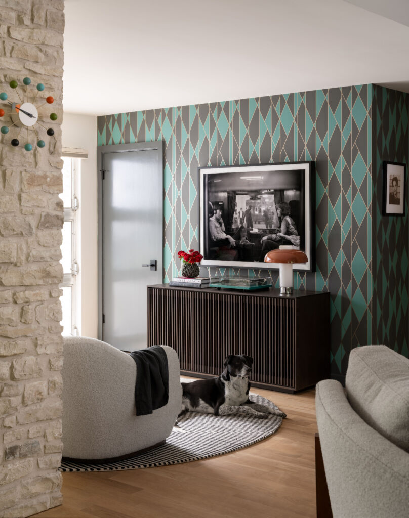 Playful patterned wallpaper adds personality to the media room, complementing the home’s layered, midcentury-inspired interiors.
